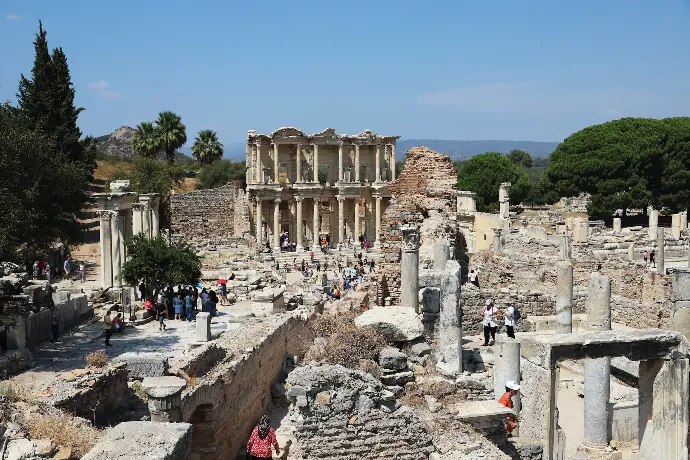 a group of people walking around a building with columns